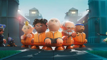 Prison Architect 2 delayed release date again: A group of prisoners lined up at the gates of a prison at night.
